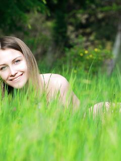 Красивая голая девушка в траве под ёлкой
