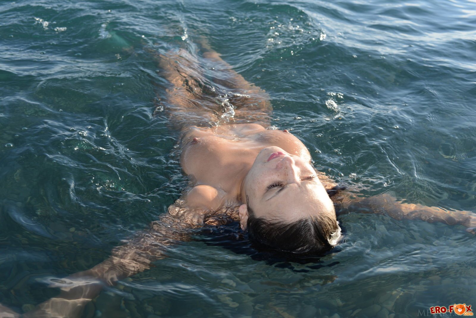 Голая девушка купается в море