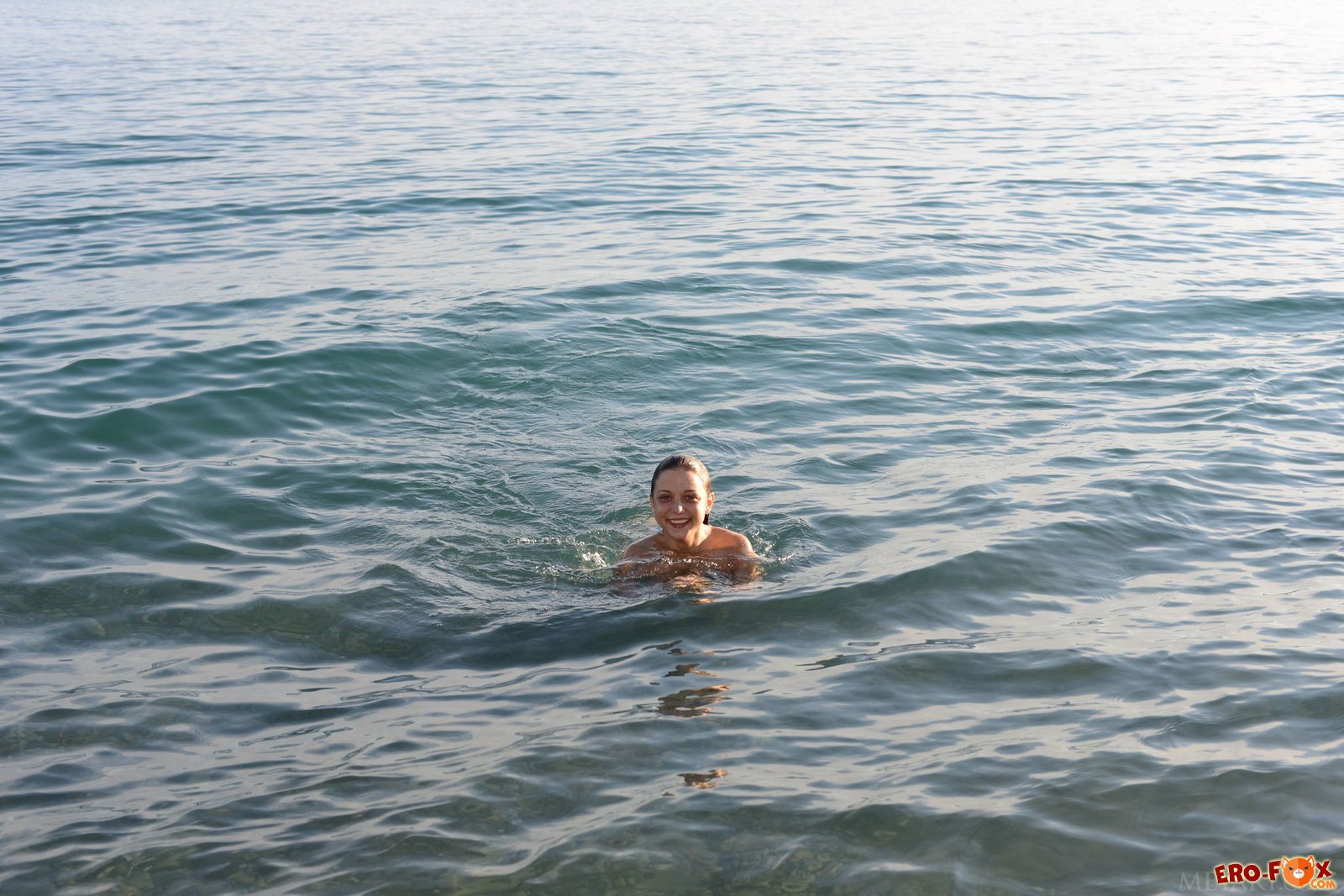 Голая девушка купается в море